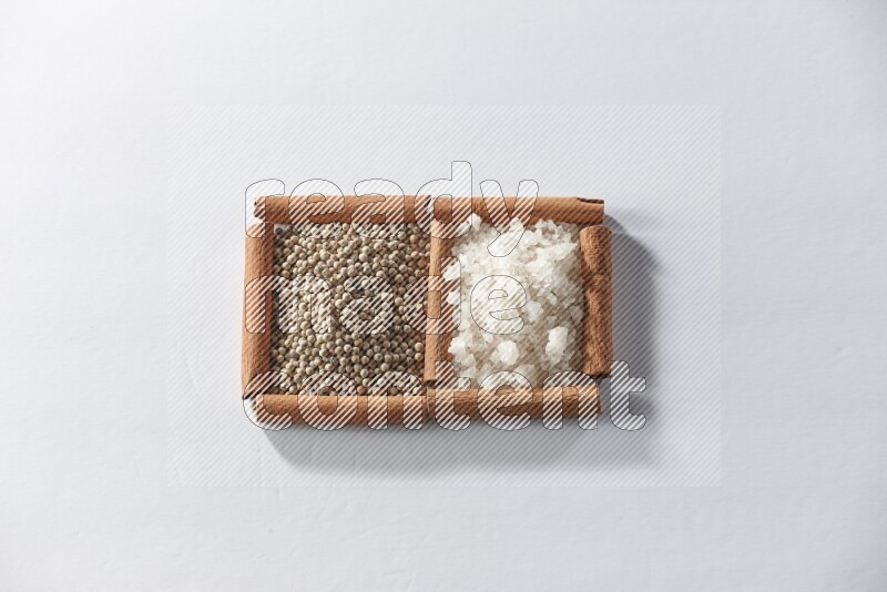 2 squares of cinnamon sticks full of white pepper and white salt on white flooring