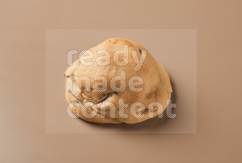 a whole chocolate chip cookie on a brown background