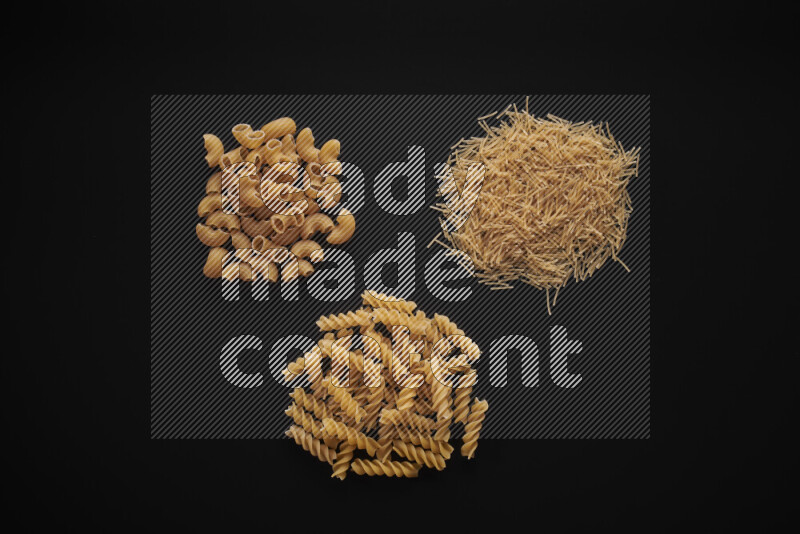 Different pasta types in bunches on black background