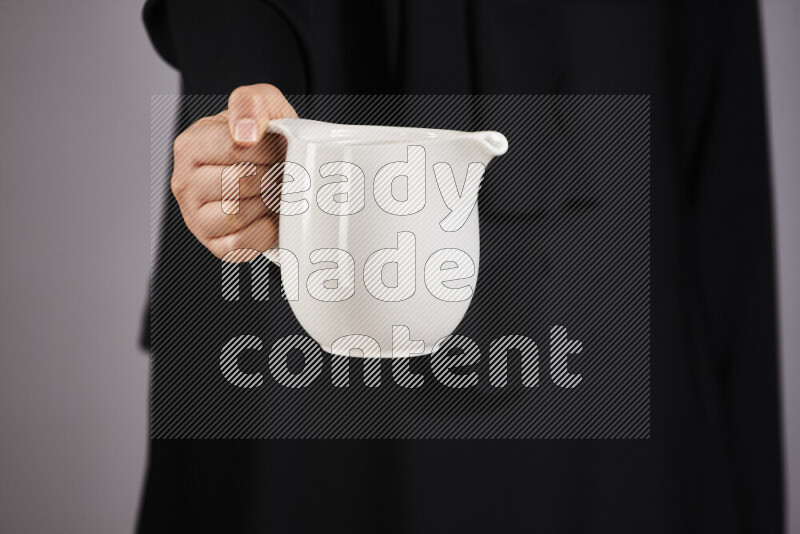 A woman in black abaya holding different pottery essentials in different positions