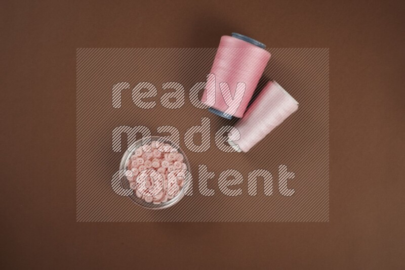 A pink collection of sewing and tailoring tools arranged on a brown background