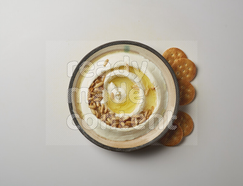 Lebnah garnished with pine nuts in a pottery plate on a white background