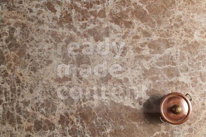 A small copper pot on beige marble background