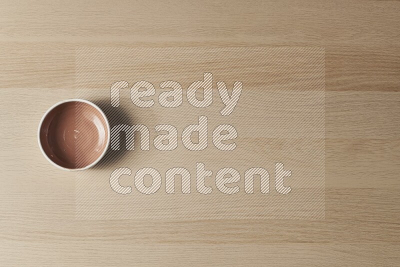 A brown pottery bowl on light wooden background