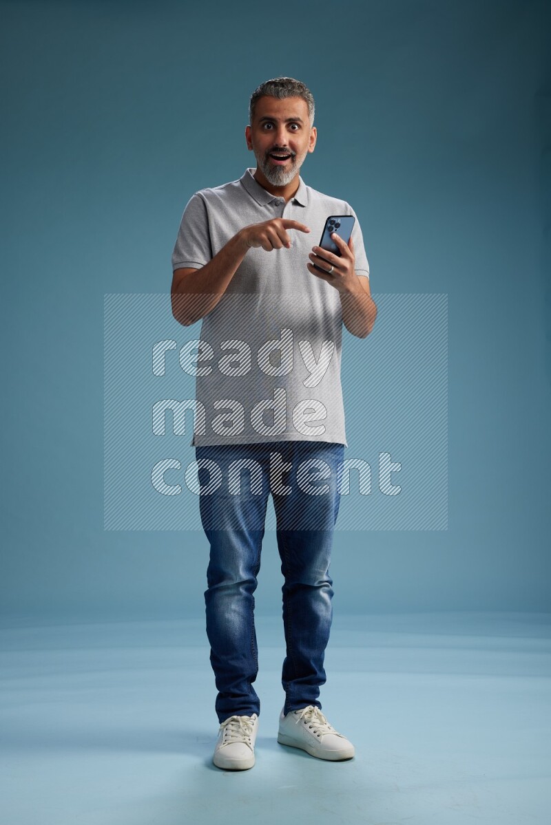 Man Standing texting on phone on blue background