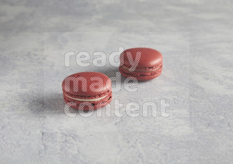 45º Shot of two Red Velvet macarons  on white  marble background