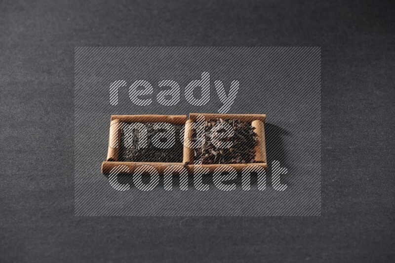 2 squares of cinnamon sticks full of tea and cloves on black flooring