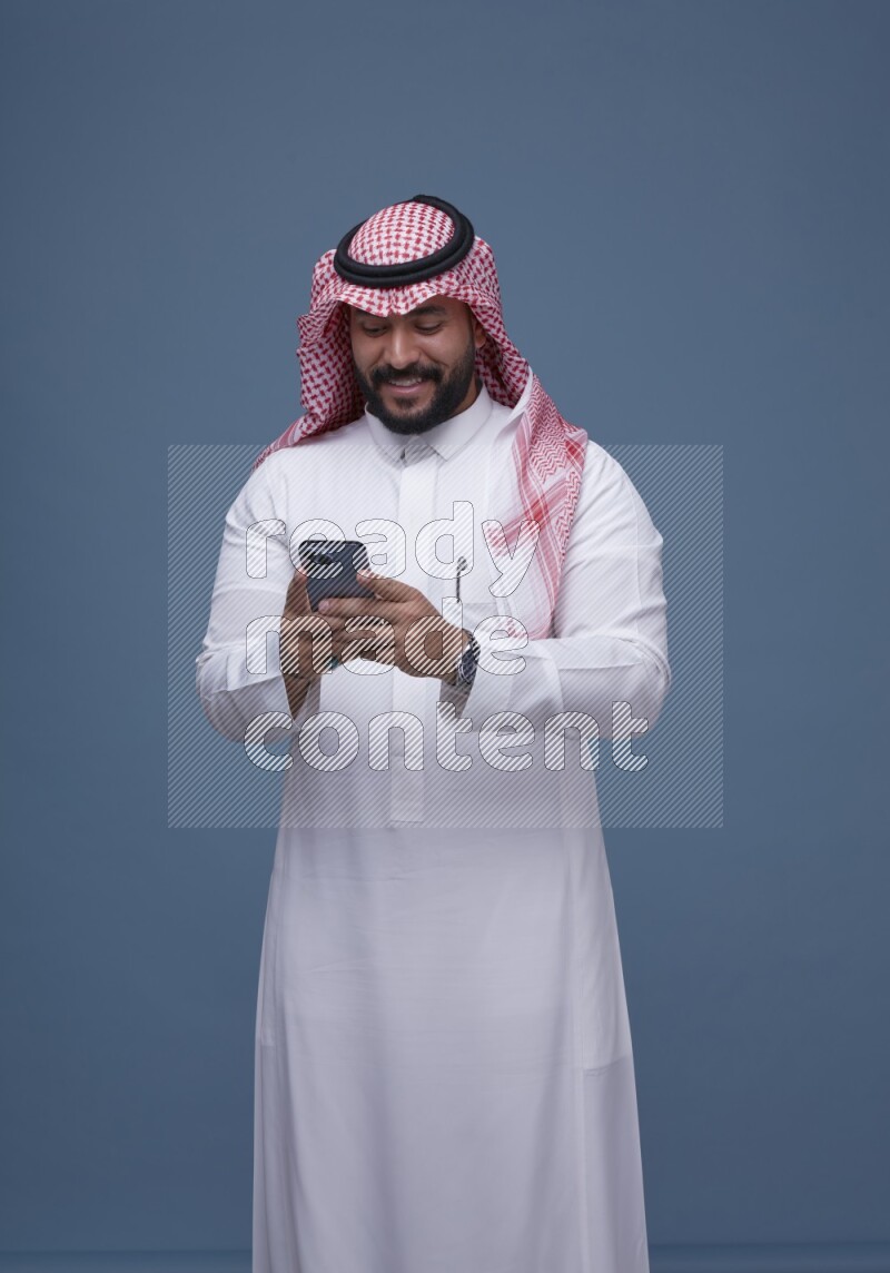 A man Texting on Blue Background wearing Saudi Thob and Shomag