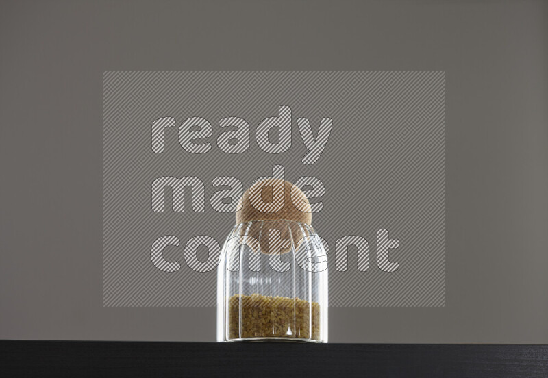 Coarse bulgur in a glass jar on black background