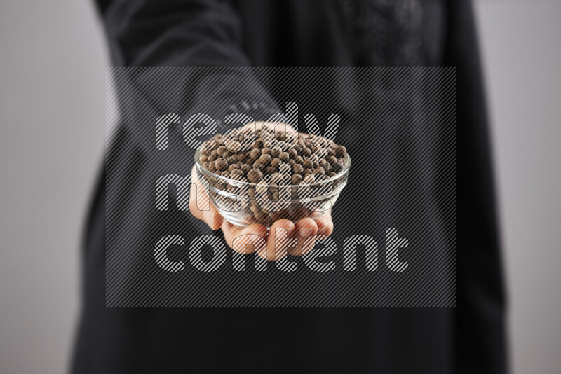 Woman in abaya holding different kinds of spices in different positions