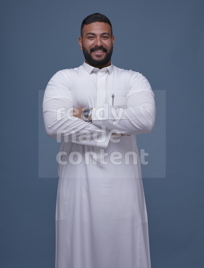 A man Posing in Blue Background wearing a Saudi Thob