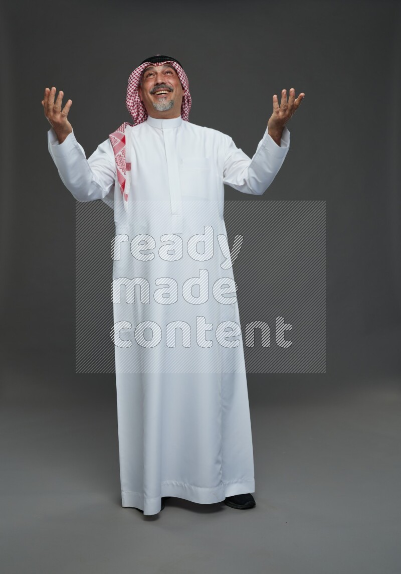 Saudi man with shomag Standing Interacting with the camera on gray background