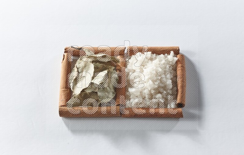 2 squares of cinnamon sticks full of white salt and laurel bay leaves on white flooring