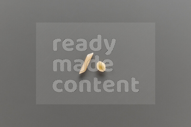 Mini penne pasta with other types of pasta on grey background
