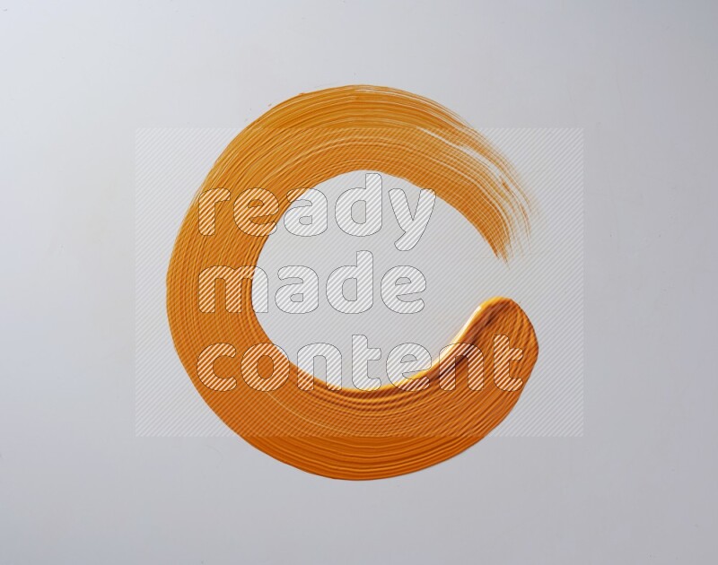 An orange circular painting brush stroke on white background