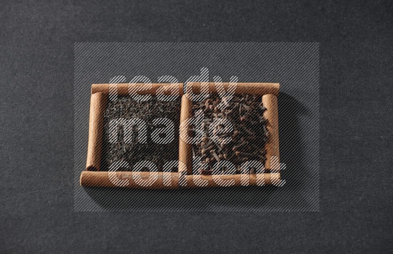 2 squares of cinnamon sticks full of tea and cloves on black flooring