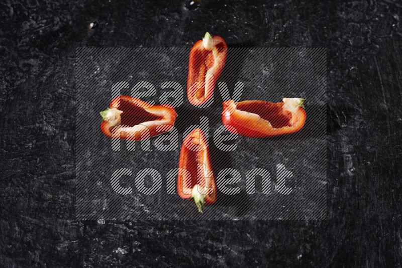 Red bell pepper slices on black background