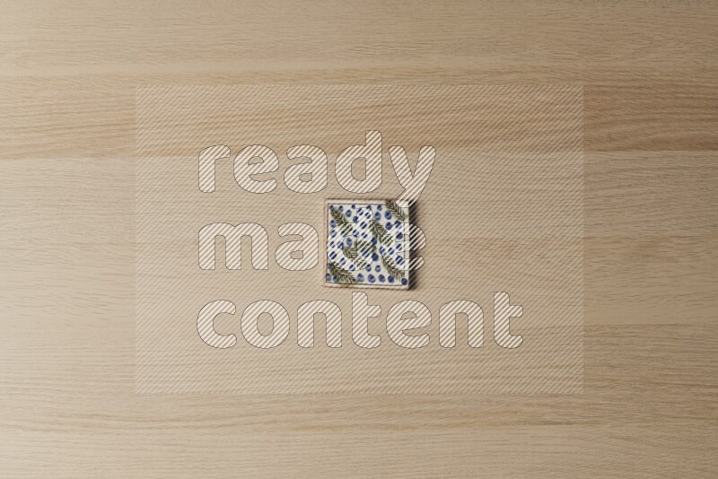 A decorative pottery coaster on light wooden background