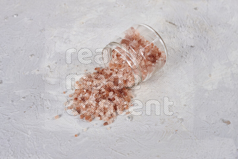 A glass jar full of coarse himalayan salt crystals on white background