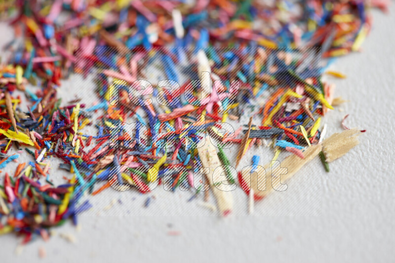This image showcases a vibrant multicolored pencil shavings scattered on grey background