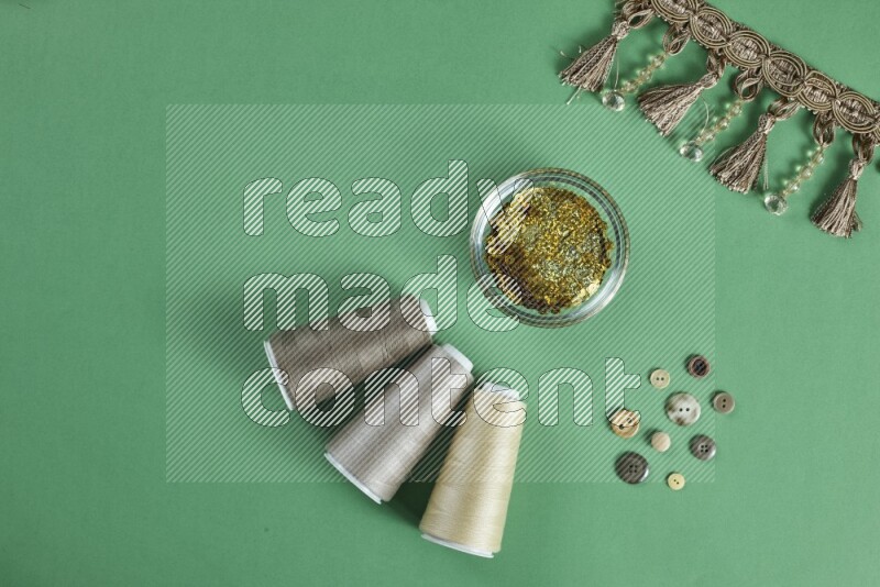 A brown collection of sewing and tailoring tools arranged on a green background