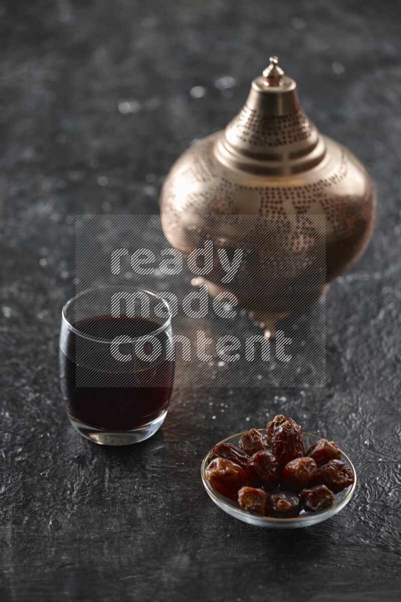 A golden lantern with different drinks, dates, nuts, prayer beads and quran on textured black background