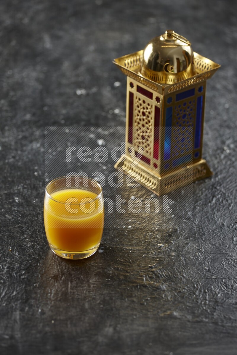 A golden lantern with different drinks, dates, nuts, prayer beads and quran on textured black background