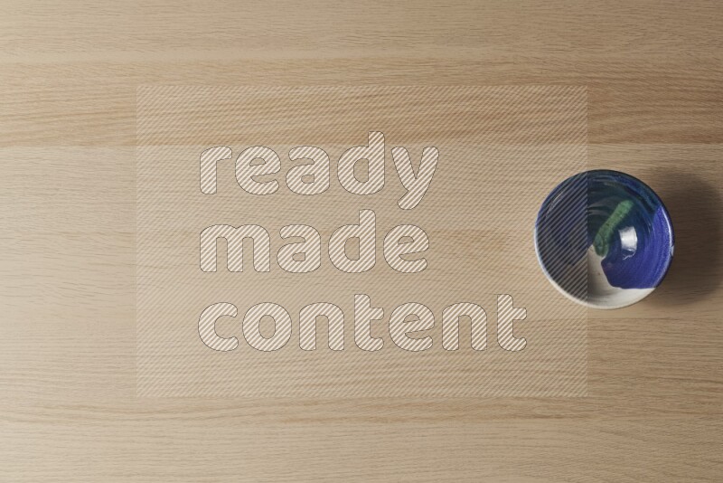 وعاء فخاري متعدد الألوان على خلفية خشبية فاتحة