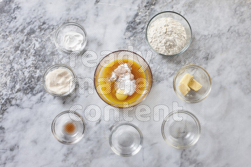 Cookies step by step with its ingredient, flour, butter, brown sugar, egg, vanilla extract, white sugar, chocolate chips and baking soda on grey marble background