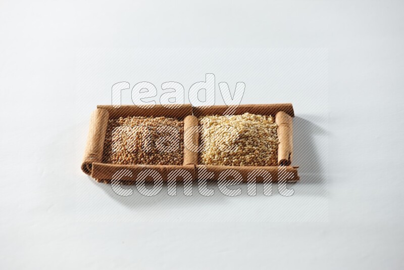 مربعان من أعواد القرفة ممتلئان بحبوب الخردل وبذور السمسم علي خلفية بيضاء