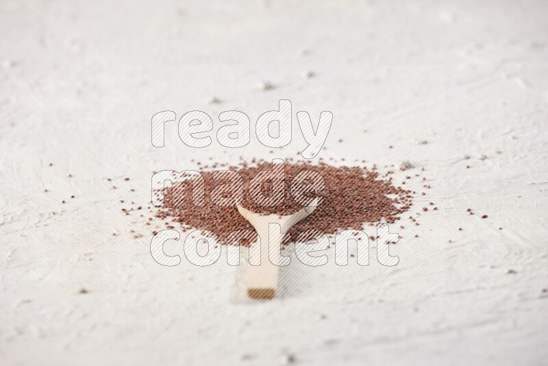 A wooden spoon full of garden cress seeds on a textured white flooring