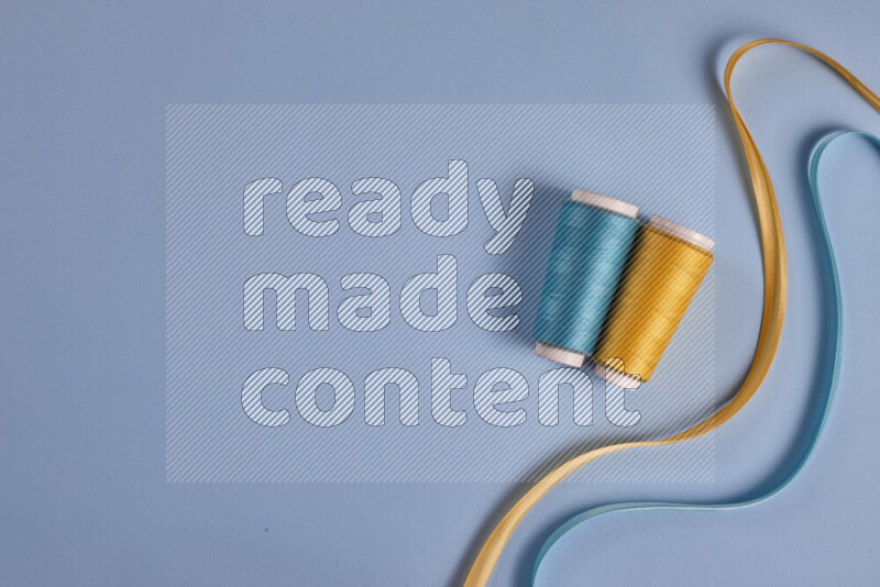 مجموعة من أدوات الخياطة والتفصيل صفراء وزرقاء اللون على خلفية زرقاء