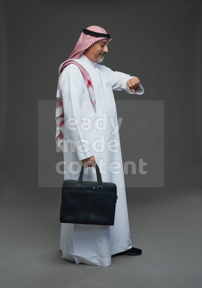 Saudi man with shomag Standing holding bag on gray background