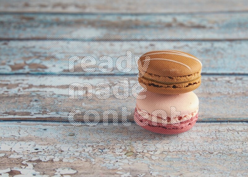 45º Shot of of two assorted Brown Irish Cream, and Pink Litchi Raspberry macarons on light blue background