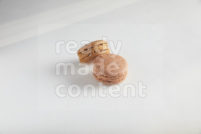 45º Shot of of two assorted Brown Irish Cream, and Brown Hazelnuts macarons on white background