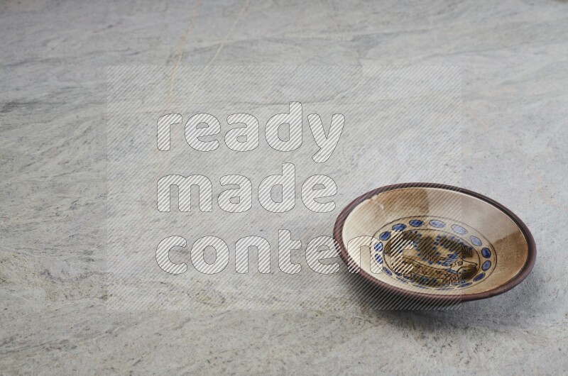 A decorative pottery plate on grey marble background