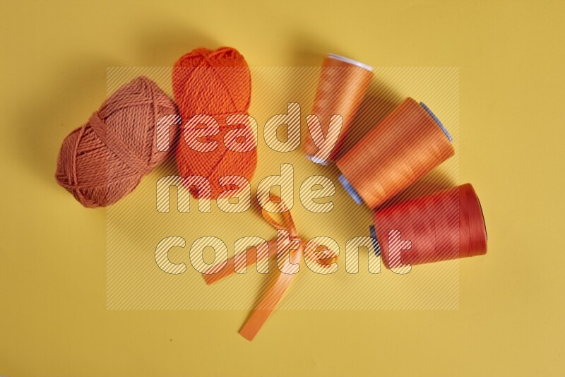An orange collection of sewing and tailoring tools arranged on a yellow background