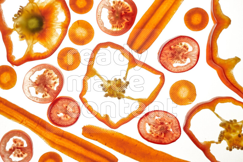 Mixed vegetables and fruits slices on illuminated white background