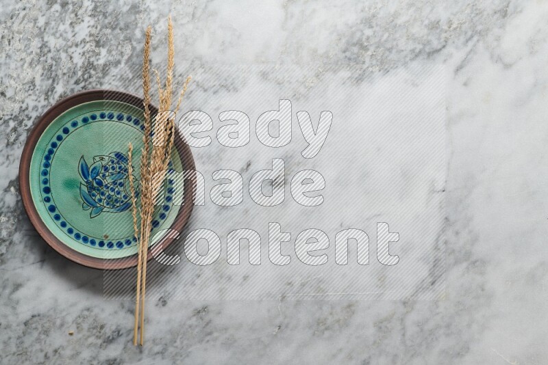 Wheat stalks on decorative pottery plate on grey marble background
