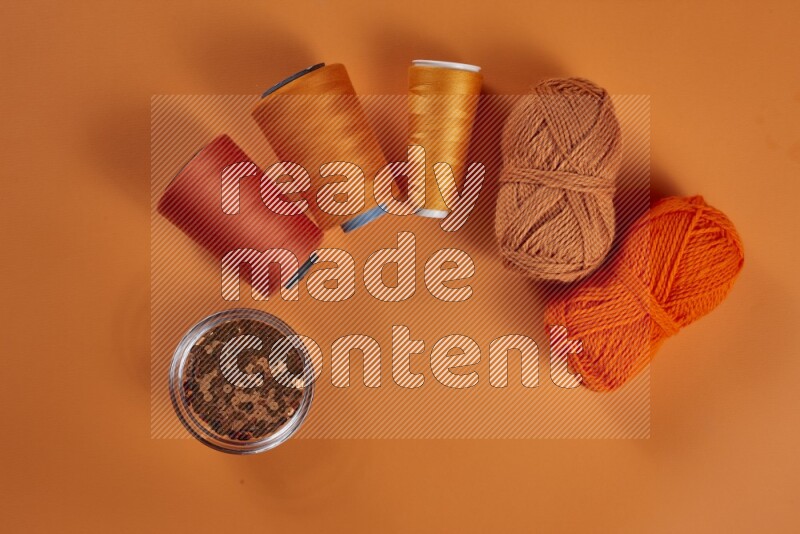An orange collection of sewing and tailoring tools arranged on a orange background