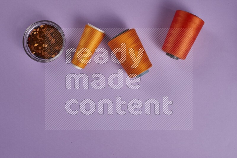 An orange collection of sewing and tailoring tools arranged on a purple background