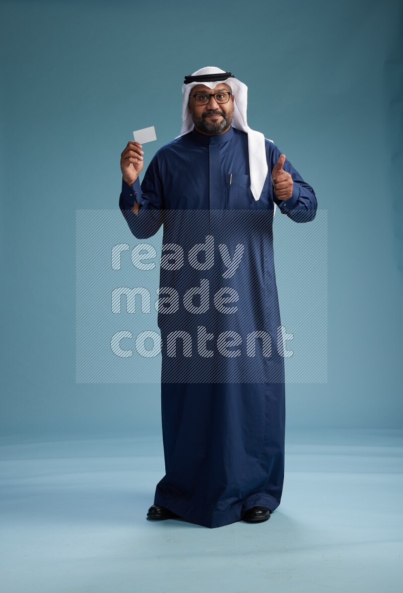 Saudi Man with shimag Standing holding ATM on blue background