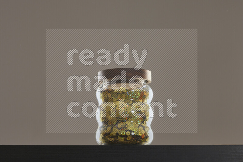 Sequins in a glass jar on black background
