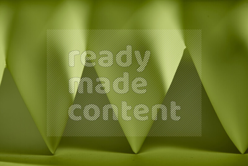 صورة مجردة مقربة تظهر طيات ورقية هندسية حادة بتدرجات اللون الأخضر