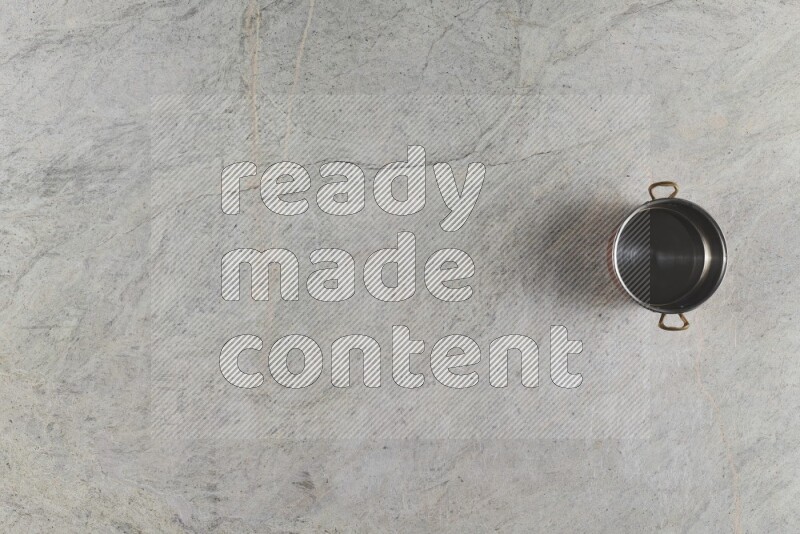 A small copper pot on grey marble background