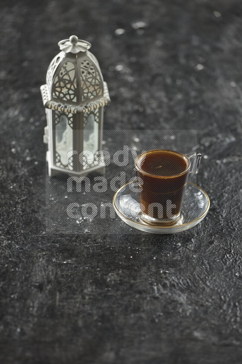 A white lantern with different drinks, dates, nuts, prayer beads and quran on textured black background