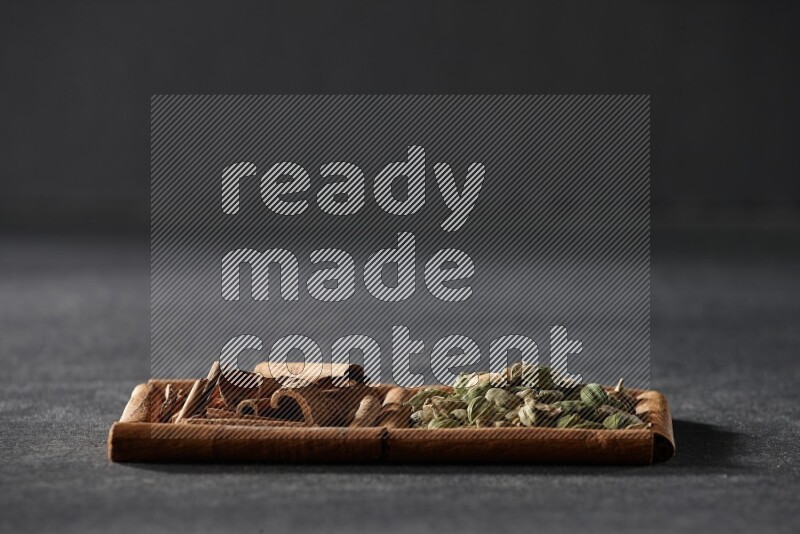 مربعان من أعواد القرفة ممتلئان بحبوب الهيل والقرفة علي خلفية سوداء