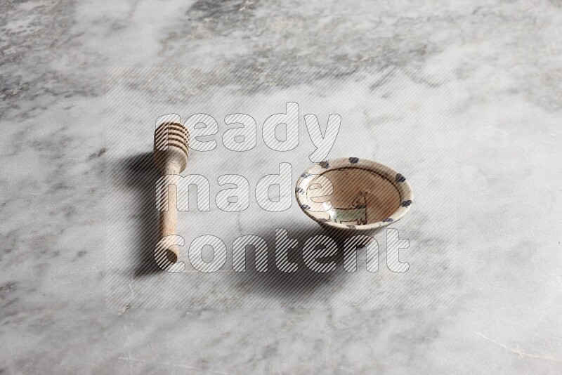Decorative pottery bowl with wooden honey dipper on the side on grey marble background