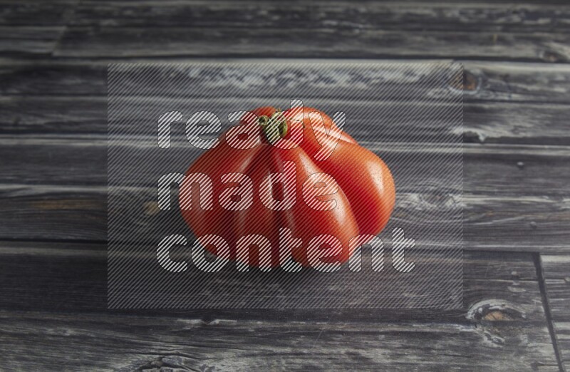 45 degree single heirloom tomato on a textured grey wooden background