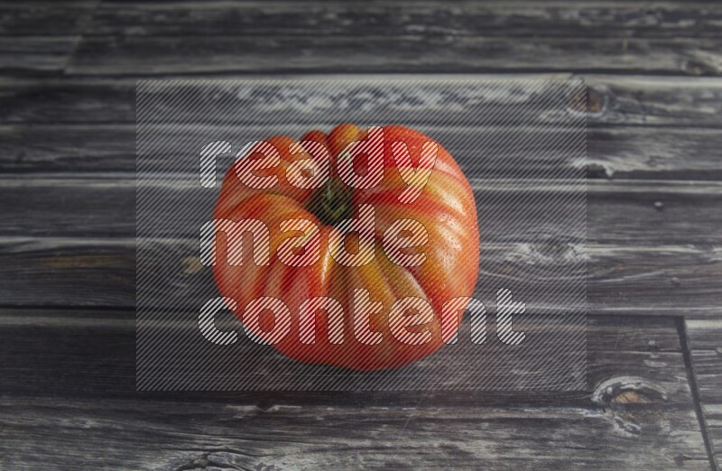 45 degree single heirloom tomato on a textured grey wooden background